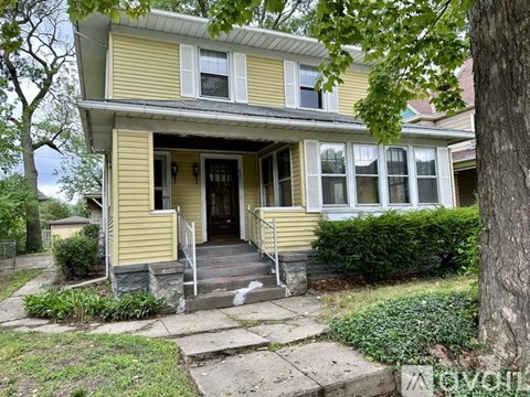 A yellow house with a white door and windows.