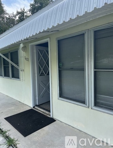 A white building with a black mat in front of it.