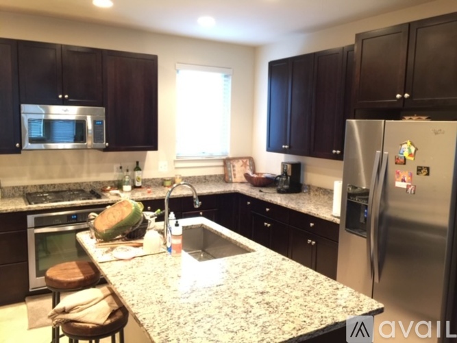 A kitchen with a granite countertop and a refrigerator with magnets on it.