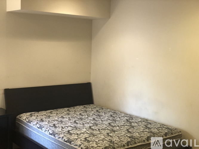 A bed with a black headboard and a floral patterned bedspread is in the image.