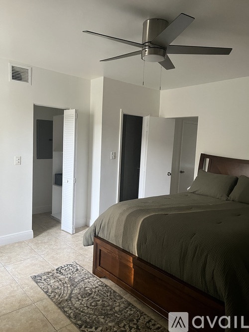 A bedroom with a bed, a ceiling fan, and a rug.