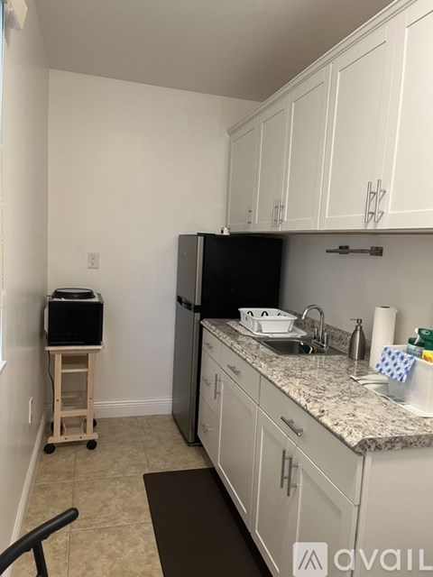 A kitchen with white cabinets and a granite countertop.