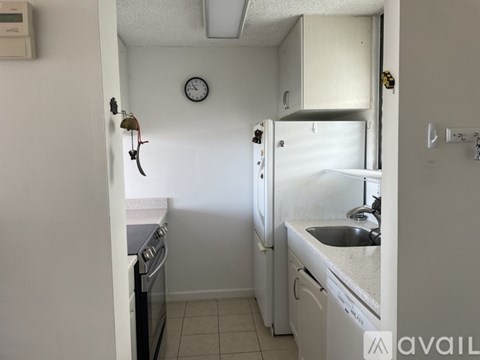 A small kitchen with a white fridge, black stove and a clock on the wall.