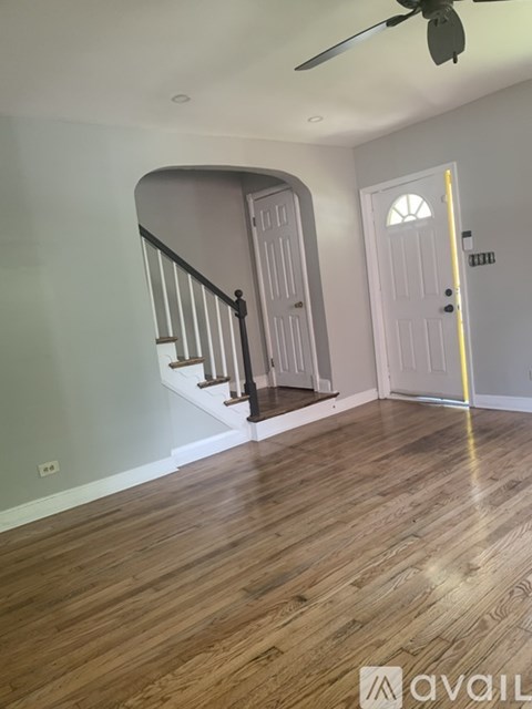 A room with a wooden floor and a staircase with a black railing.