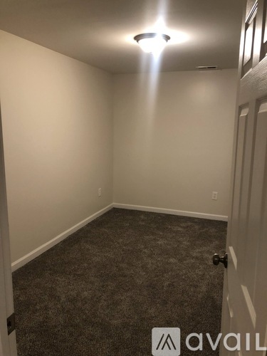 A room with carpeted floor and a door on the right.