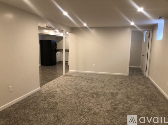 A spacious room with carpeted floor and white walls.