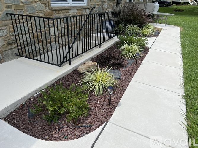A black metal fence borders a landscaped garden bed.