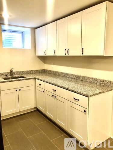 A kitchen with white cabinets and a granite countertop.
