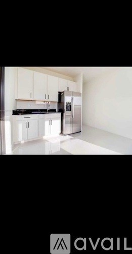 A kitchen with white cabinets and a black fridge.
