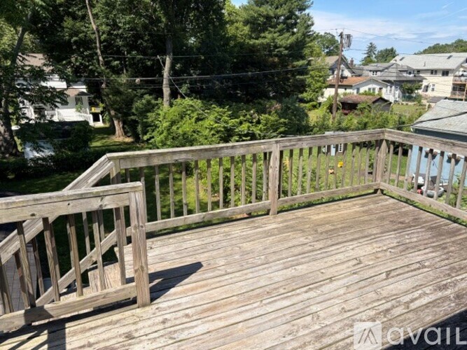 A wooden deck with a railing and trees in the background.
