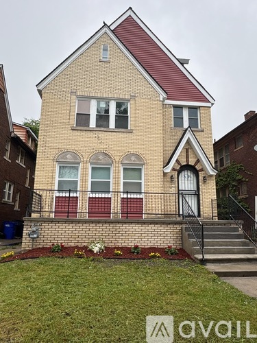 A brick house with a red roof and a sign that says "avail" in front of it.