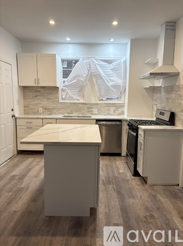 A kitchen with a white countertop and wooden flooring.