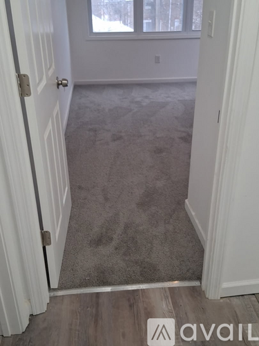 A hallway with a carpeted floor and white walls.