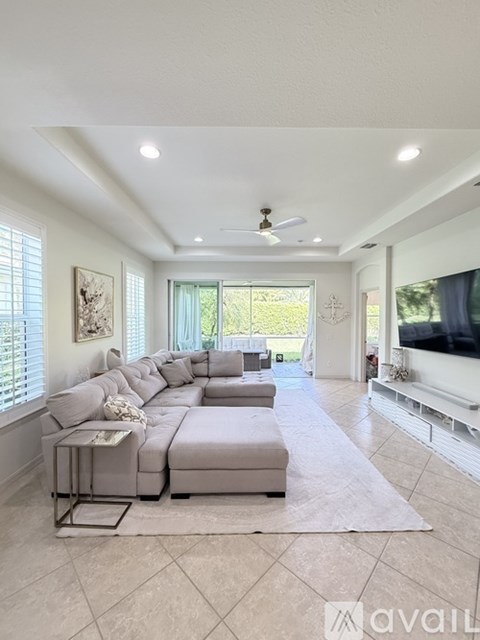 A spacious living room with a grey sofa set and a television.