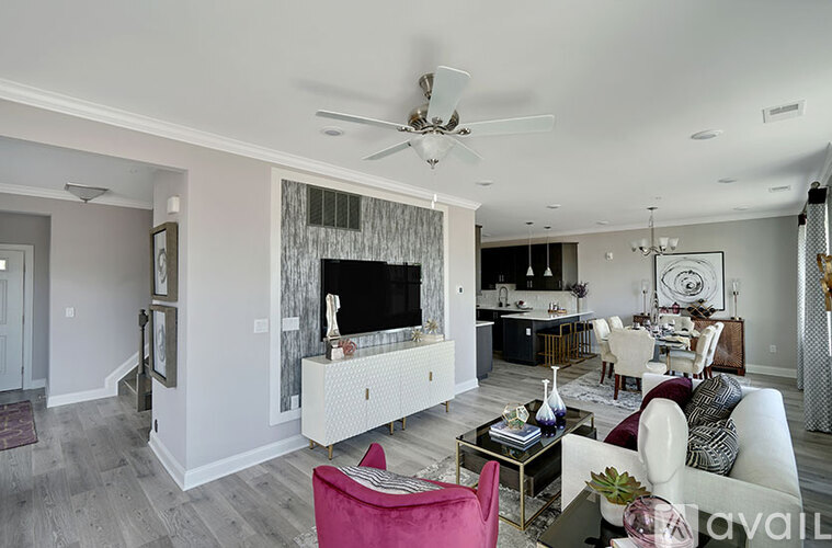 A living room with a pink chair and a white sofa.