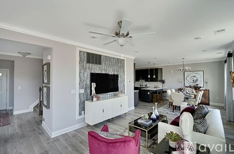 A living room with a pink chair and a white sofa.