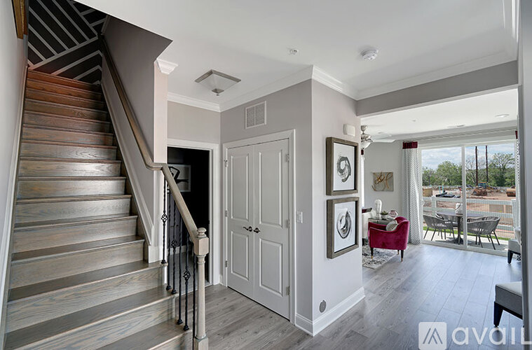 A staircase with wooden steps and a metal railing leads to a room with a white door and a picture on the wall.