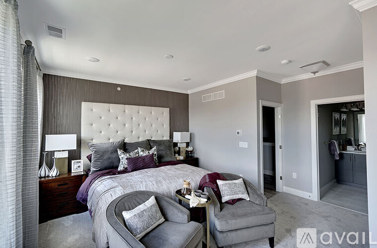 A bedroom with a large bed and a grey chair.
