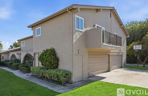A beige two-story house with a garage door and a balcony.