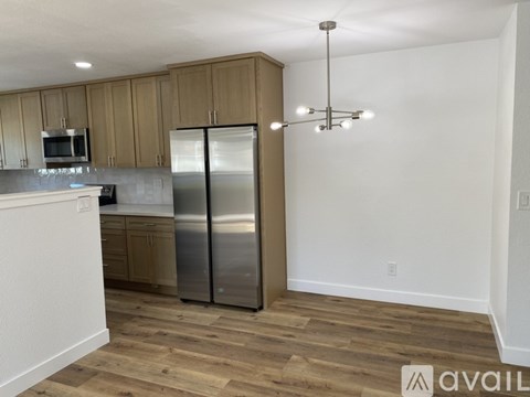 A kitchen with wooden cabinets and a stainless steel refrigerator.