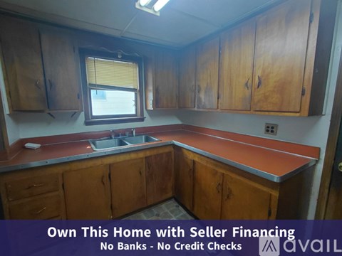 A kitchen with wooden cabinets and a sink is for sale with seller financing.