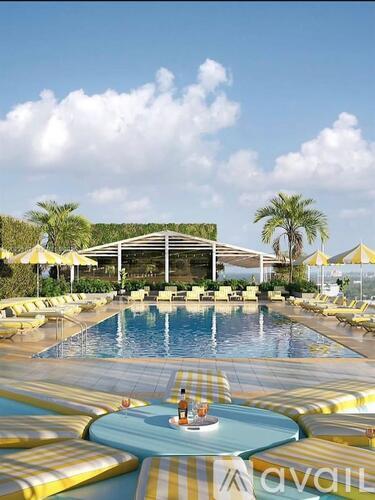 A large outdoor pool with a hot tub in the middle and a building in the background.