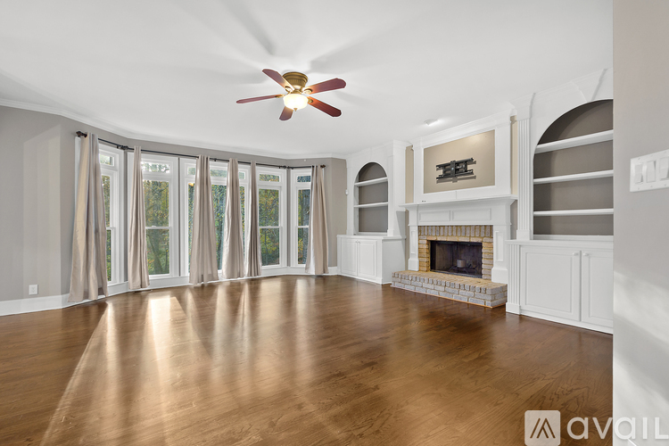 A spacious room with a fireplace and a fan on the ceiling.