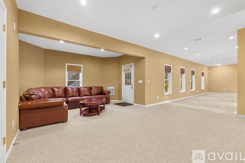 A living room with a brown leather couch and a carpeted floor.
