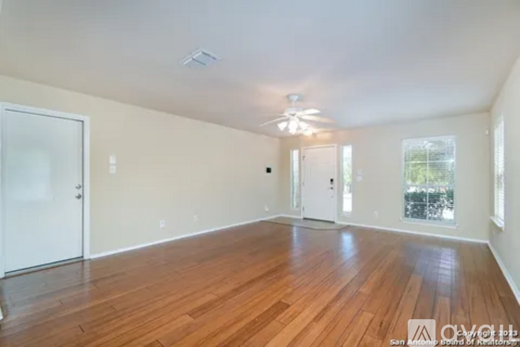 A spacious room with wooden flooring and white walls.
