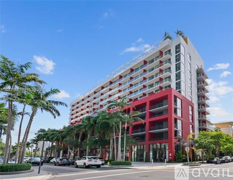 A red and white building with palm trees in front.