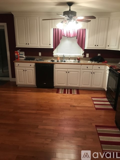 A kitchen with wooden floors and white cabinets.