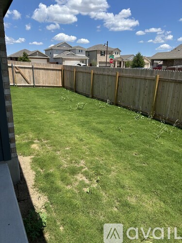 A backyard with a wooden fence and a grassy area.