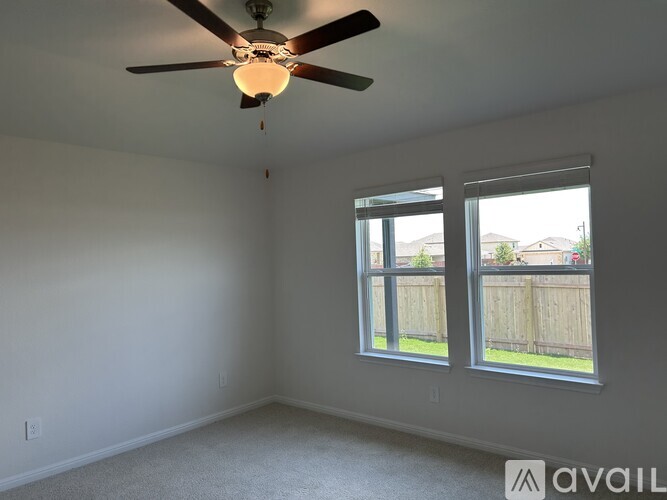 A room with a ceiling fan and two windows.