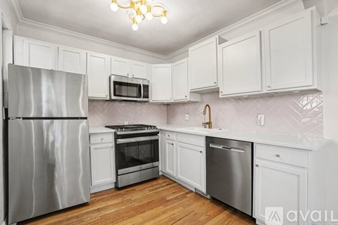 A kitchen with white cabinets and a stainless steel refrigerator.