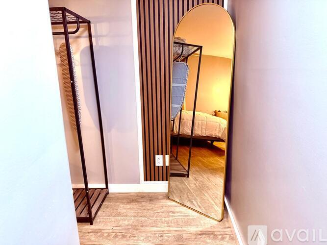 A large mirror reflects a bedroom with a bed and a striped wall.