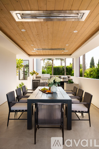 A modern dining room with a wooden ceiling and a long table with chairs.