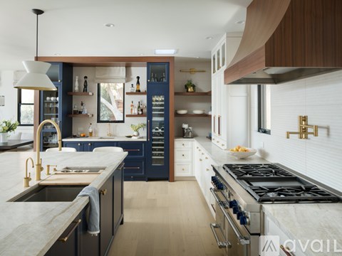 A modern kitchen with dark blue cabinets and a white countertop.