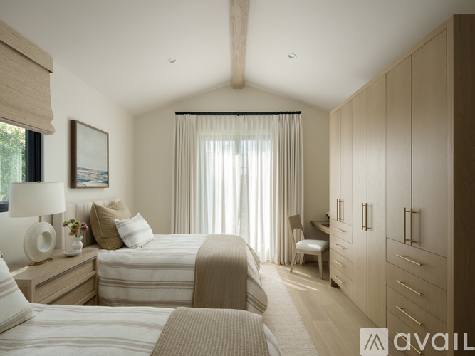 A bedroom with two beds, a desk, and a chair.