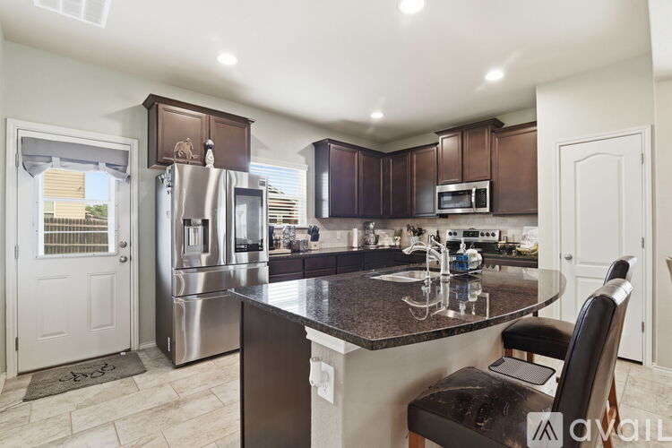 A kitchen with brown cabinets and a black countertop.