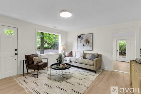 A living room with a brown chair, a white couch, and a coffee table in the center.
