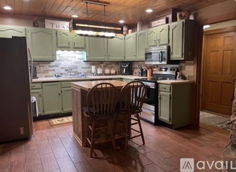 A kitchen with green cabinets and a wooden floor.