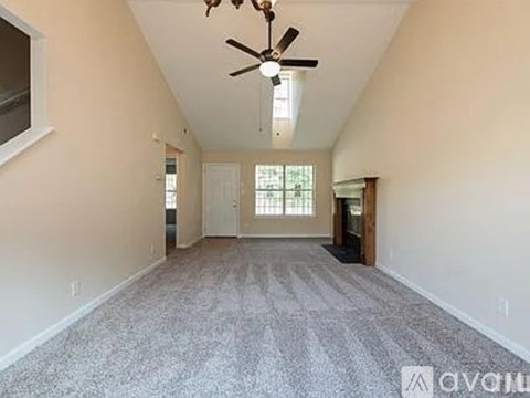 A spacious room with a ceiling fan and carpeted floor.