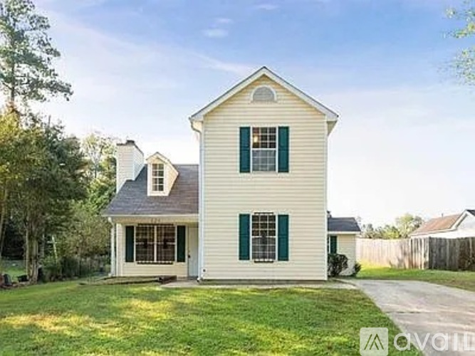 A two-story house with a white exterior and green shutters.