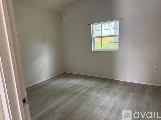A room with a window and wooden flooring is available for rent.