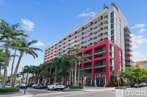 A tall red and white building with palm trees in front.