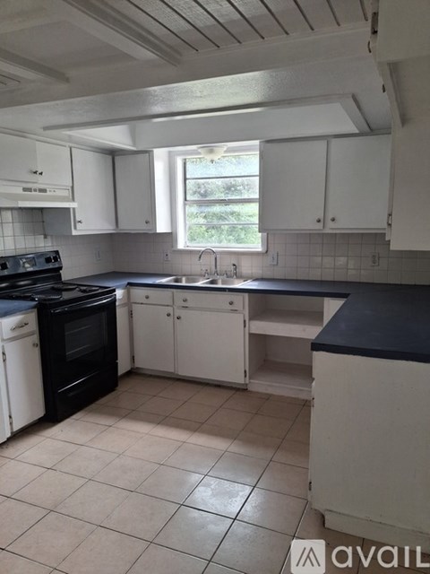 A kitchen with white cabinets and black appliances.