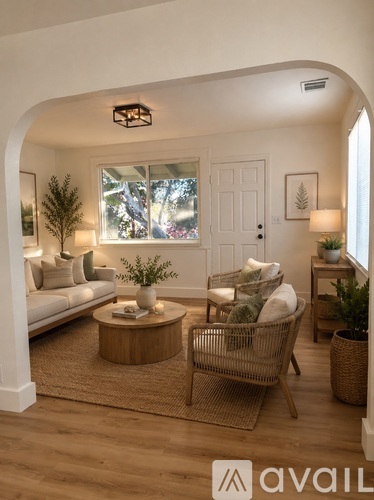 A living room with a white sofa, a wooden coffee table, and a wicker chair.