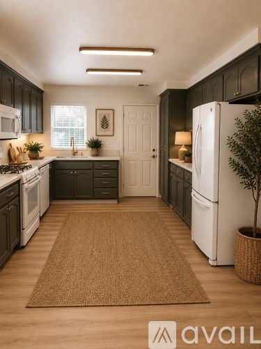 A kitchen with a white refrigerator and black cabinets.