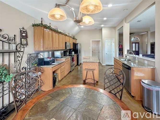 A kitchen with a stone floor and wooden cabinets.