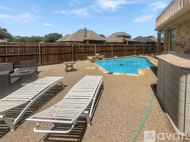 A backyard with a pool and sun loungers.